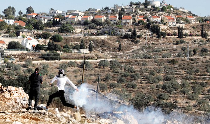 金曜日、週毎に行われるイスラエルによるパレスチナの土地接収への抗議デモの後、イスラエル軍と衝突している覆面を付けたパレスチナ人の抗議者。(AFP)