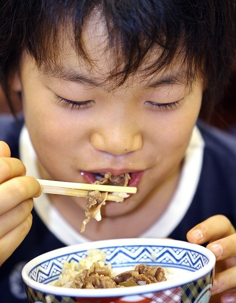 2006年9月18日、東京のファーストフードレストランの吉野家で、ご飯に牛肉を乗せた、いわゆる「牛丼」を食べている日本人の男の子。（AFP/ファイル）