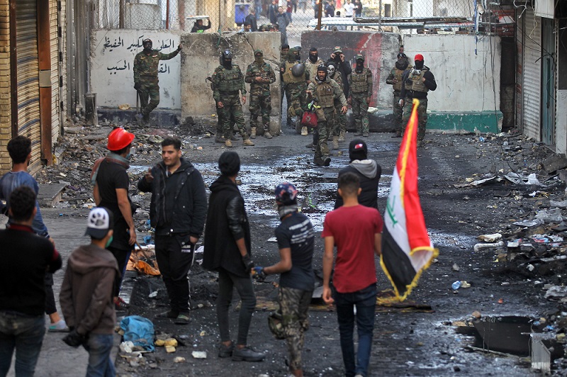 2019年12月5日、イラクの治安部隊と反政府抗議者は、小康状態時に首都バグダットのal-Rasheed通りにあるコンクリート製の壁の前に集まった。(AFP)