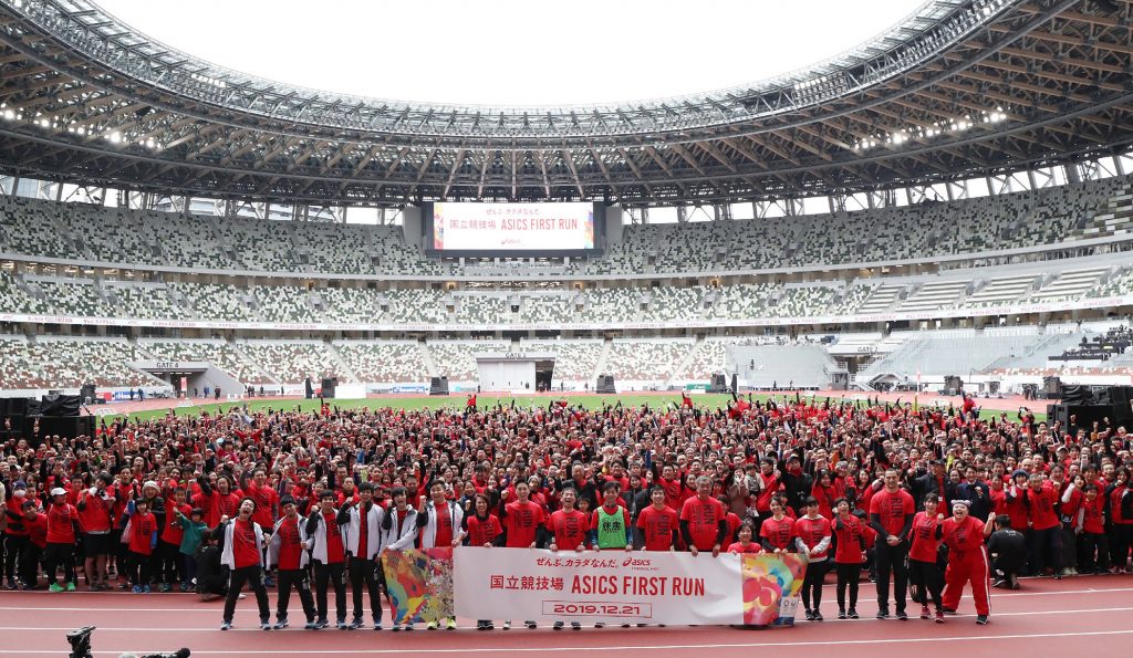 2019年12月21日に東京で開催された、東京2020オリンピック大会の会場となる新国立競技場での「初めてのレース」イベント中、トラックの上でカメラに向かってポーズする参加者たち（時事通信社/AFP）