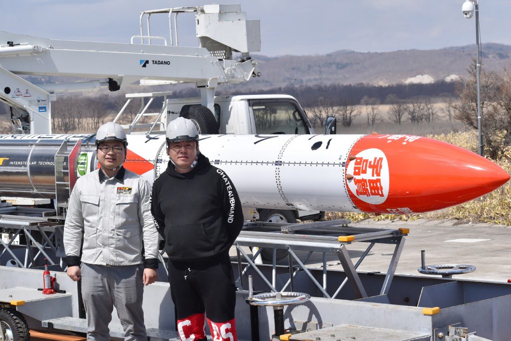 2019年4月12日、北海道大樹町においてMOMO3号機ロケットの前でポーズを取る、インターステラテクノロジズ社最高経営責任者の稲川貴大氏(左)と創業者の堀江貴文氏(右)。(時事通信社 / AFP)