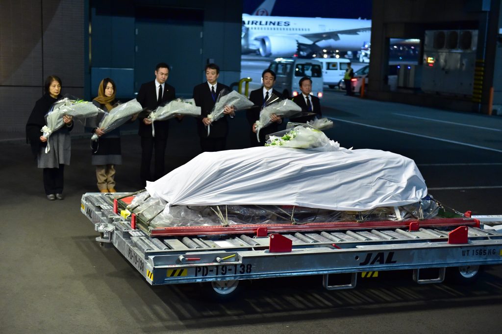2019年12月8日に千葉県の成田空港で、亡くなった日本人医師の中村哲氏の親類や政府関係者たちが棺の前に花束をささげる。（AFP通信）