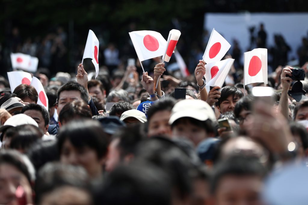 2019年5月4日、東京の皇居で即位した皇太子殿下と雅子皇后の姿を見るため、初公開に先立って即位を祝う多くの人たちが集まって日本の国旗を掲げている。(AFP)