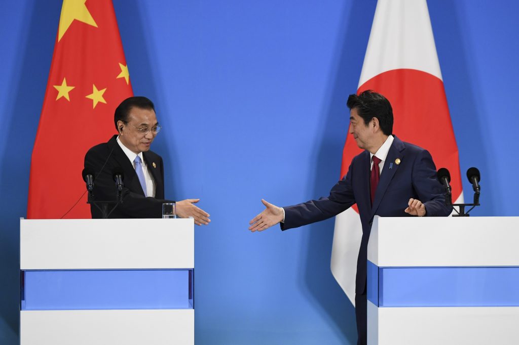 中国の李克強首相(左)が、2019年12月24日に中国四川省の南西で行われた中国、韓国、日本の第8回三国首脳会議での共同記者会見で、日本の安倍晋三首相と握手を交わす。(AFP)