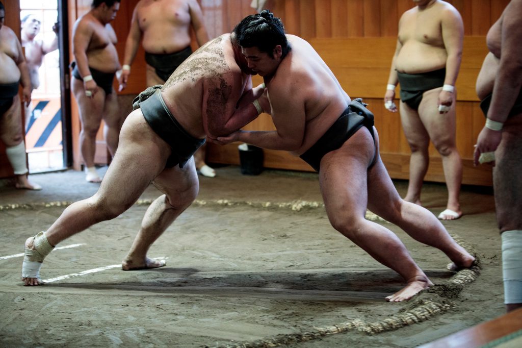 東京の相撲部屋での稽古シーン。たがいを土俵から押し出そうとしている力士ら。2019年8月28日。（AFP）