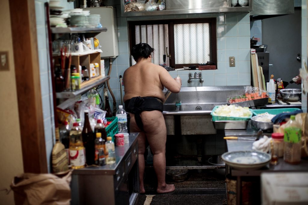 東京の相撲部屋で。稽古後の朝食の準備のため台所に立つ力士。2019年8月28日。（AFP）
