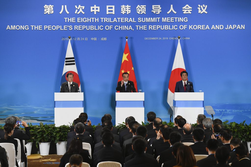 2019年12月24日、成都における第8回3カ国首脳会談での共同記者会見で、韓国の文在寅大統領（左）と日本の安倍晋三首相（右）が見守る中、中国の李克強首相が話をする。 (AFP) 