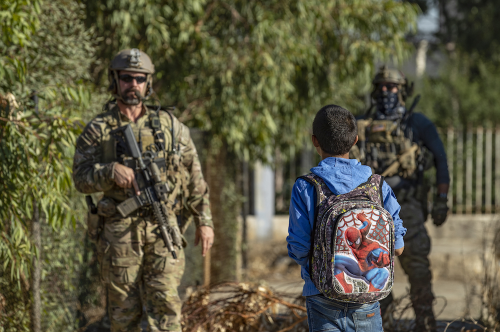 シリア北東、ハサカ県のアイン・ディワルの村をパトロールするアメリカ兵を見つめるシリアの少年（AFP）