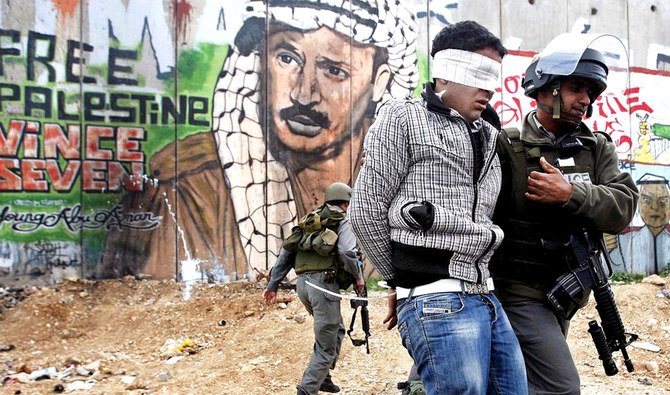 問題のイスラエルの分離壁の前でパレスチナ人を拘束するイスラエルの国境警察官。ICCは木曜日、戦争犯罪の加害者を裁きに掛けることに乗り出した。（ロイター通信）