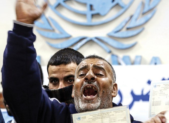 ガザで2014年の紛争中に壊れた家の補償を求めたデモでスローガンを叫ぶパレスチナ人  (AFP通信)