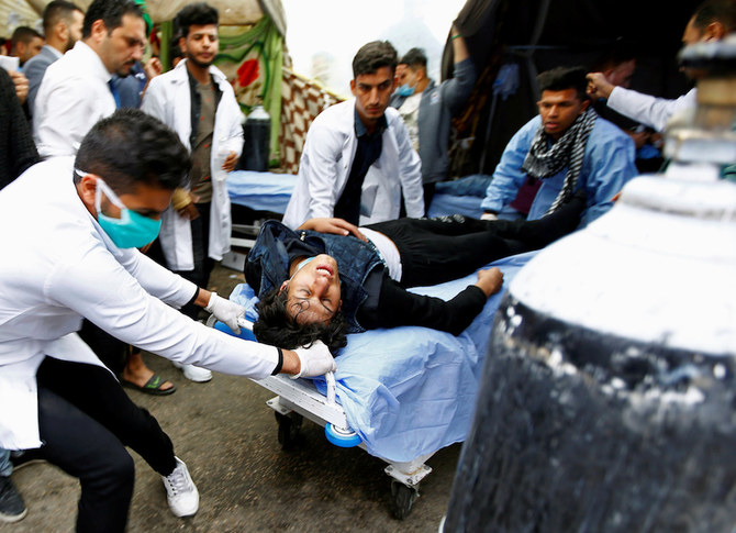 日曜日、ナジャフで続く反政府デモの最中に負傷者を運ぶ医療担当者 (ロイター)