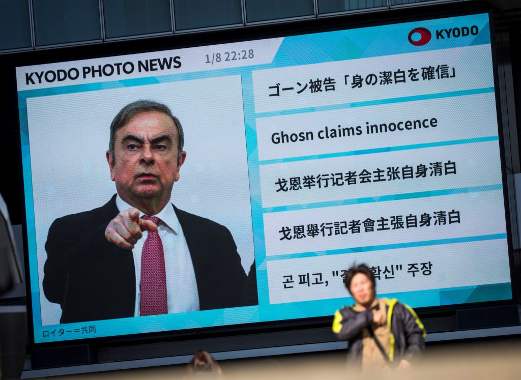 カルロス・ゴーン元日産会長のニュースを報じる巨大スクリーンを通り過ぎる歩行者。2020年1月9日　東京。（AFP通信）