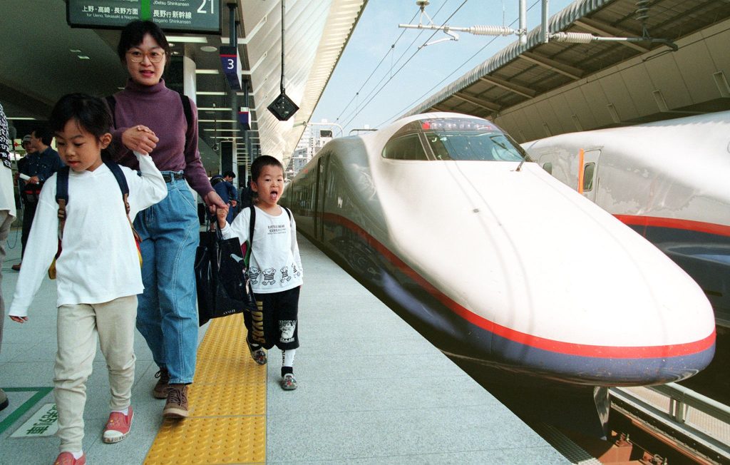 1998年に、東京と220km北西の長野とを結ぶ長野新幹線「あさま」を家族連れが通り過ぎる。(AFP通信)