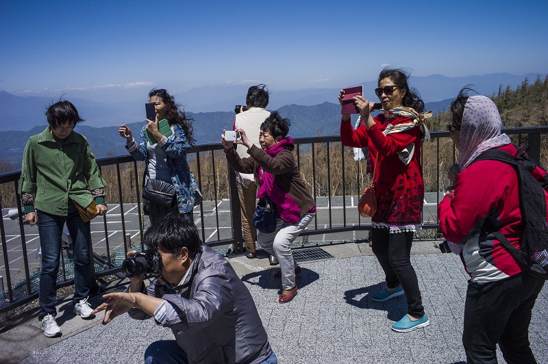 2015年5月13日、富士河口湖で富士山の写真を撮る中国人観光客。日本の観光産業は、中国が最近の肺炎の大流行を機に海外団体ツアーを禁じた影響への備えを進めている。（AFP / ファイル）