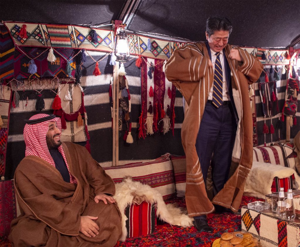 サウジアラビアのムハンマド・ビン・サルマン皇太子が見ている中、安倍晋三首相がサウジのトーブを試着する様子。（提供）