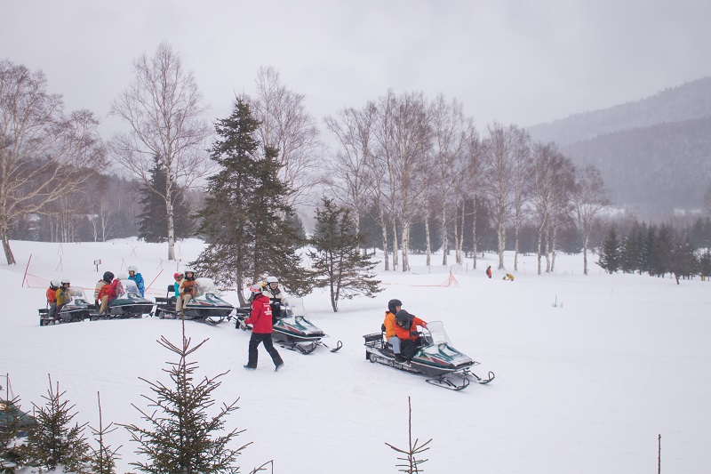 日本の北海道のトマムスキーリゾートの雪の谷でスノーモービルを楽しむ観光客。(Shutterstock)