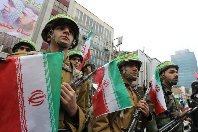 イランの準軍事組織の民兵部隊、バスィージの隊員が国旗を持ち、テヘランの元大使館の前をバスィージの国家的週を記して行進する。(ファイル/AFP)