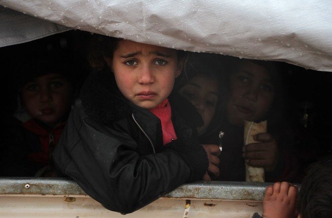 イドリブ県南部のマアッラト・アン＝ヌウマーンで政府軍の攻勢から逃れ、同県ハーブヌーシュの村の近くの避難民キャンプにトラックの荷台に乗ってたどり着き、複雑な表情を見せるシリア人の子供。（File：AFP）