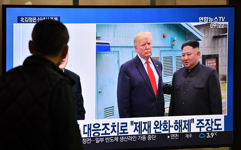  パンムンジョムの停戦村で開催されたドナルド・トランプ米大統領と金正恩朝鮮労働党委員長間の会談映像を報じるテレビニュース番組を観る男性。2020年1月1日、ソウル市内の鉄道駅にて。（AFP）