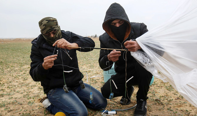 イスラエルとガザとの国境近くの、ガザ地区南部ラファの東で17日、抗議活動の一部としてイスラエル側に飛ばす物を準備しているパレスチナ人の男性。（AFP）