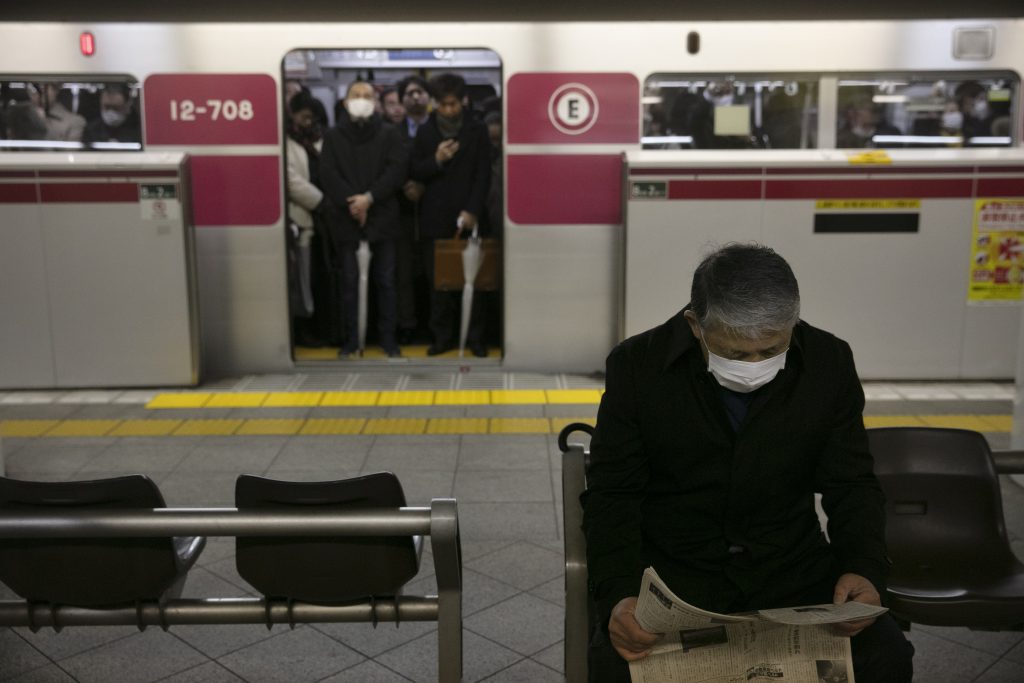 東京の朝のラッシュ時、電車が到着するのを待っている間に、新聞を読むマスクをした通勤者。2020年1月28日火曜撮影。中国は火曜、新たなウイルス性疾患による死者が25人増えたと発表。また、感染の中心地の都市から米国民を避難させる準備を米国政府が進めている。（AP）