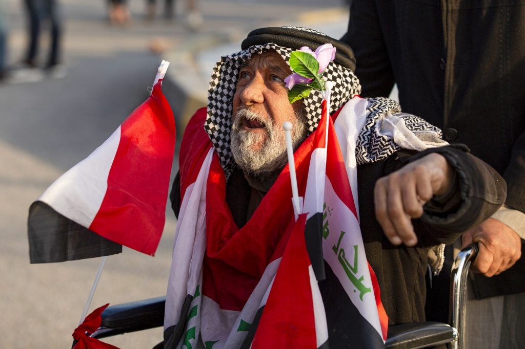 2019年12月30日、イラク南部の都市バスラで、車椅子でデモに参加する、国旗を身にまとったイラク人の男。(AFP)
