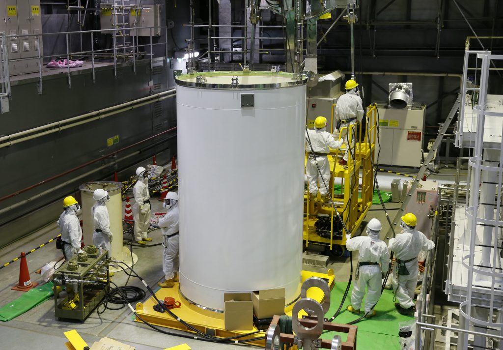 防護服を着た作業員たちが、2013年11月7日に日本の福島第一原発で、使用済み核燃料除去の準備で輸送容器とクレーンを点検している。（AFP通信）