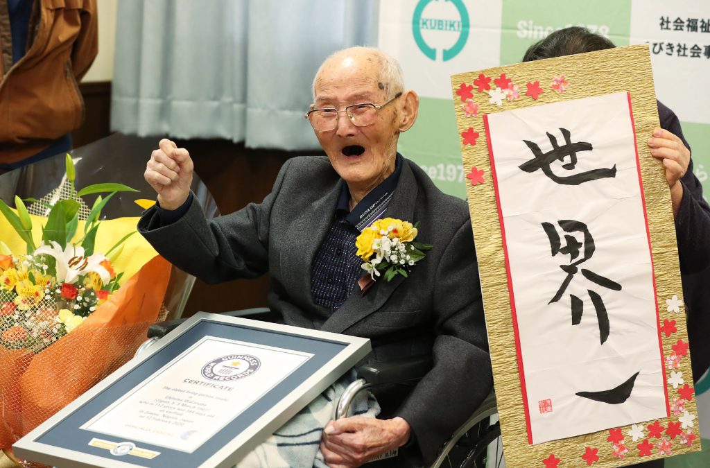2020年2月12日、世界最高齢と認定され、新潟県上越市で「世界一」の書の横でポーズをとる112歳の日本人男性渡辺智哲さん。写真は時事通信より。(AFP)