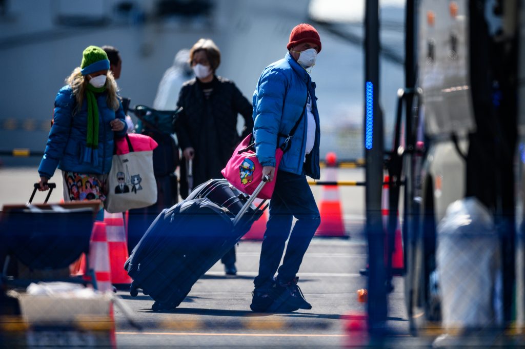 マスク着用した乗客、ダイヤモンド・プリンセスから下船後バスに乗る準備。新型コロナウイルスの恐れで隔離へ。2020年2月21日横浜港大黒ふ頭にて。(AFP)