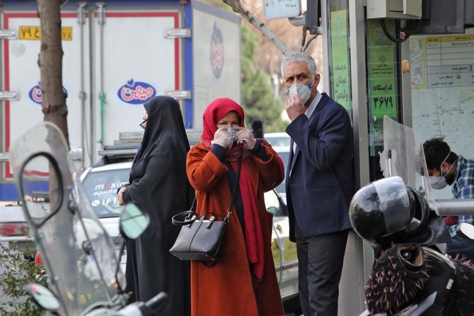 2020年2月24日、イランの首都テヘランの道路わきで予防マスクをして待つ人々。イラン政府は24日、中国以外で最も致命的なコロナウイルスCOVID-19の発生を隠蔽したとして非難されたのを受け、透明性の確保を約束し、被害は50人に上る可能性があるとする主張をしりぞけた。(AFP)