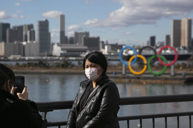 わずか5ヶ月余りでオリンピックが開幕となり、聖火リレーは日本で来月開始となる。上では、マスクをした旅行者が東京のお台場地区でオリンピックの五輪を背景に写真のポーズを取っている。(AP通信)
