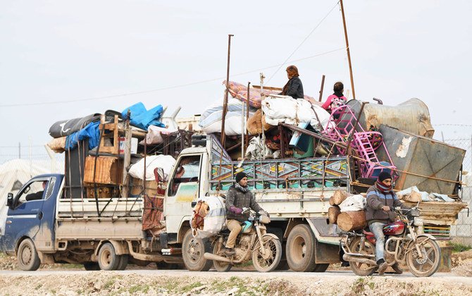 トラックの後ろに乗り シリア政府軍の前進から逃れる人々。2020年2月16日、シリア北部アレッポ州のトルコ国境近くの町デイル・バルート近郊で。（AFP）