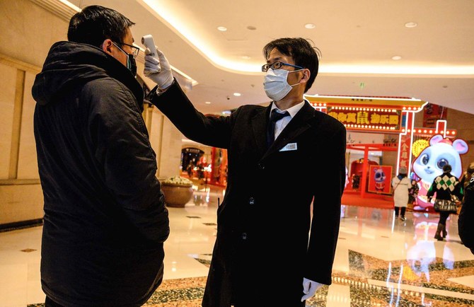 2020年、2月8日、上海のショッピングモールにて、警備員が男性の体温を確認している(AFP)