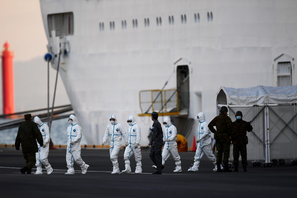 クルーズ船「ダイヤモンド・プリンセス」の周辺で、防護服姿で作業する人たち＝１２日午前、横浜市の大黒ふ頭