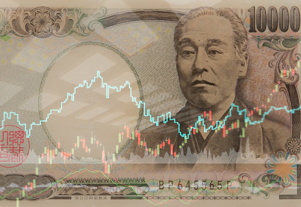 日本の通貨である円と、証券市場の取引グラフ。（シャッターストック）