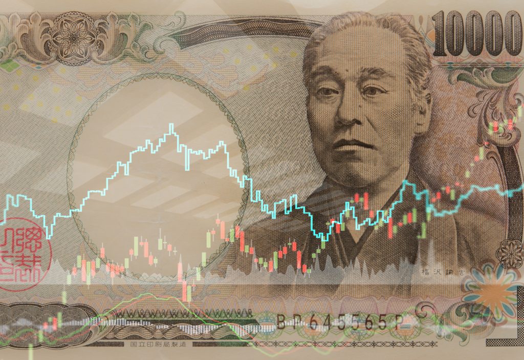 日本の通貨である円と、証券市場の取引グラフ。(シャッターストック)