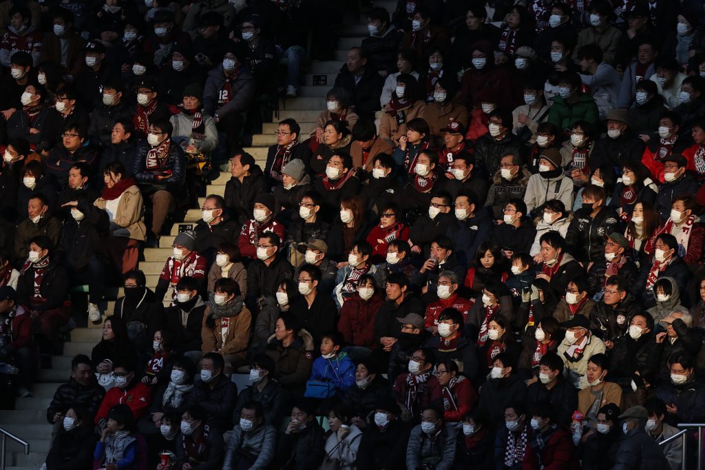 2020年2月23日に撮影された写真には、神戸で行われたサッカーJリーグのヴィッセル神戸と横浜マリノスとの試合でフェイスマスクをする観客の姿が写っている。(AFP通信)