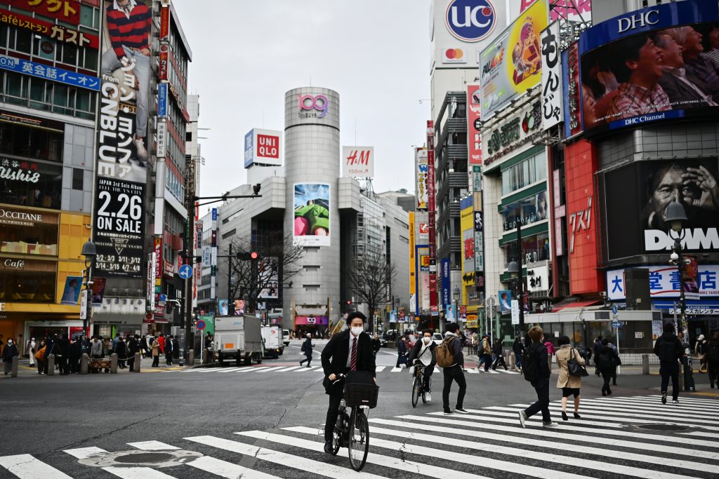 2020年3月9日に、東京の渋谷でマスクをつけた男性が自転車に乗って横断歩道を渡っている。(AFP)