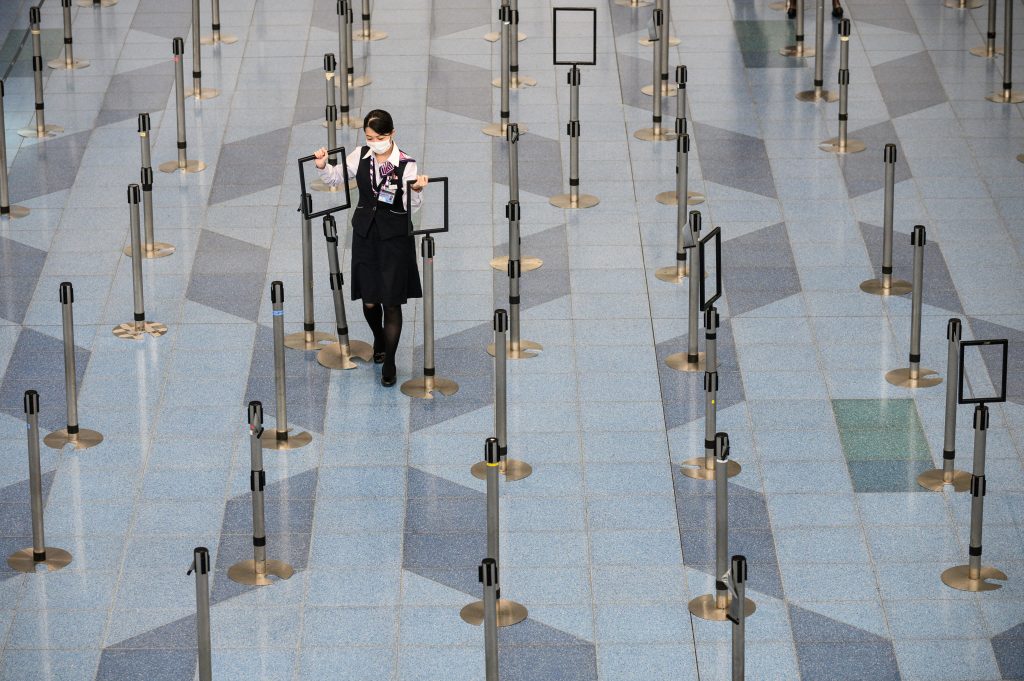 東京・羽田空港の出発ロビーでマスクを着けながら業務にあたる航空会社職員。2020年3月10日撮影。（AFP通信）