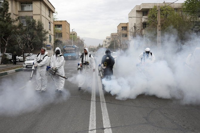 イランの新年「ノウルーズ」に先駆け、コロナウイルス（COVID-19）感染の恐れがあるなか防護マスクを着用して道路を消毒する消防隊員たち。（ロイター）
