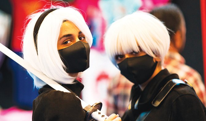 剣を振り回すアニメのキャラクターに扮し、マスクを身に着けた2人の女性が、ドバイの中東映画＆コミコンでポーズをとる。（AP）