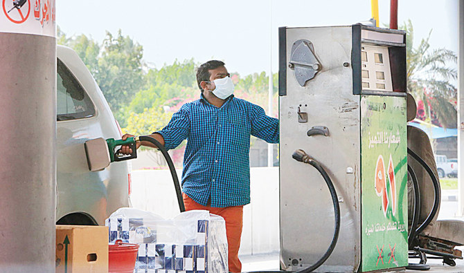 リヤドから400kmほど離れたサウジアラビア東部のカティフ市のガソリンスタンドで、予防マスクを着けた外国人作業員が車に給油している。（AFP通信）