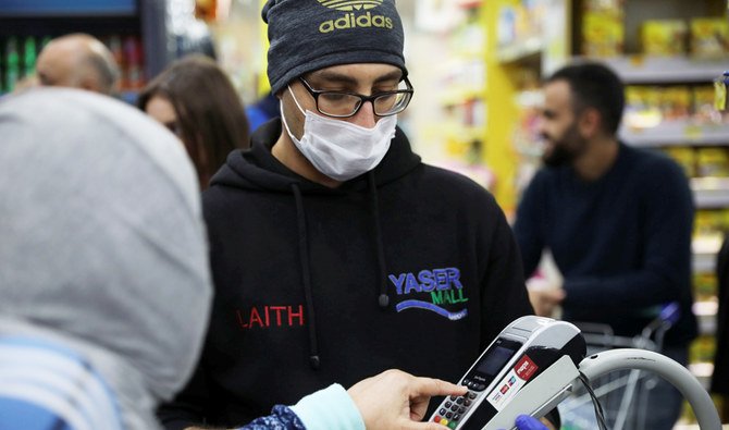 コロナウイルス（COVID-19）流行が懸念される中、フェイスマスクを着用してショッピングモールで働くレジ係、アンマン、ヨルダン、2020年3月15日（REUTERS）