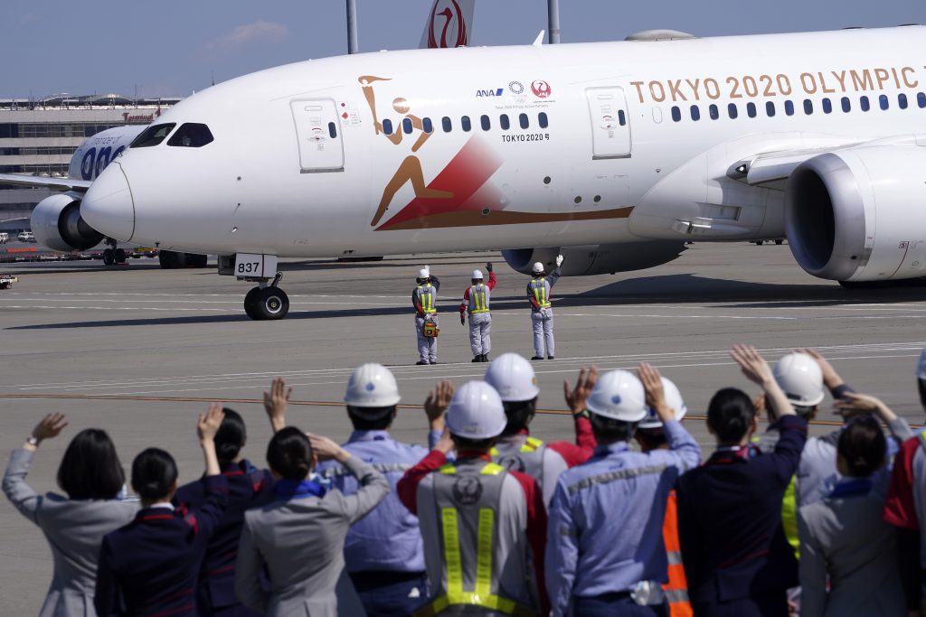 日本の航空会社の空港作業員らが、聖火をギリシャから日本へと運ぶ「Tokyo 2020 Go」特別機に手を振る様子。2020年3月18日東京の羽田東京国際空港にて。(File photo/AP)