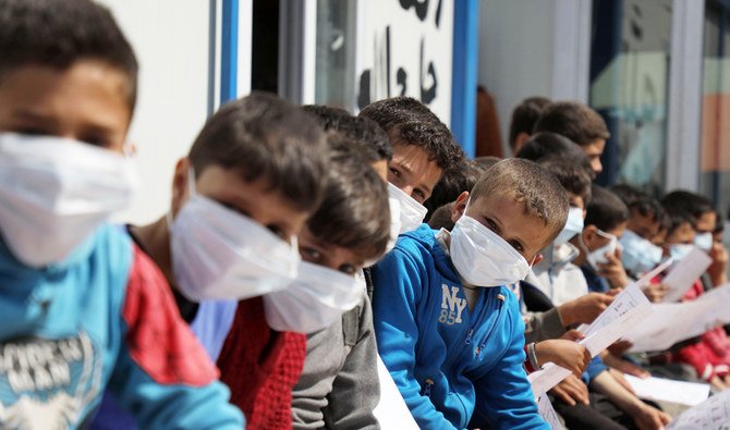 2020年3月16日、イドリブ県のトルコとの国境近くのシリアの町、アトメ近郊のキャンプで、トルコ公認のシリアの慈善援助組織所属の医療ボランティア主催のワークショップに参加する、行き場をなくしたシリア人の親子たち。このワークショップの目的は、新型コロナウィルス感染症とその予防対策への関心を広めることにある。(AFP)