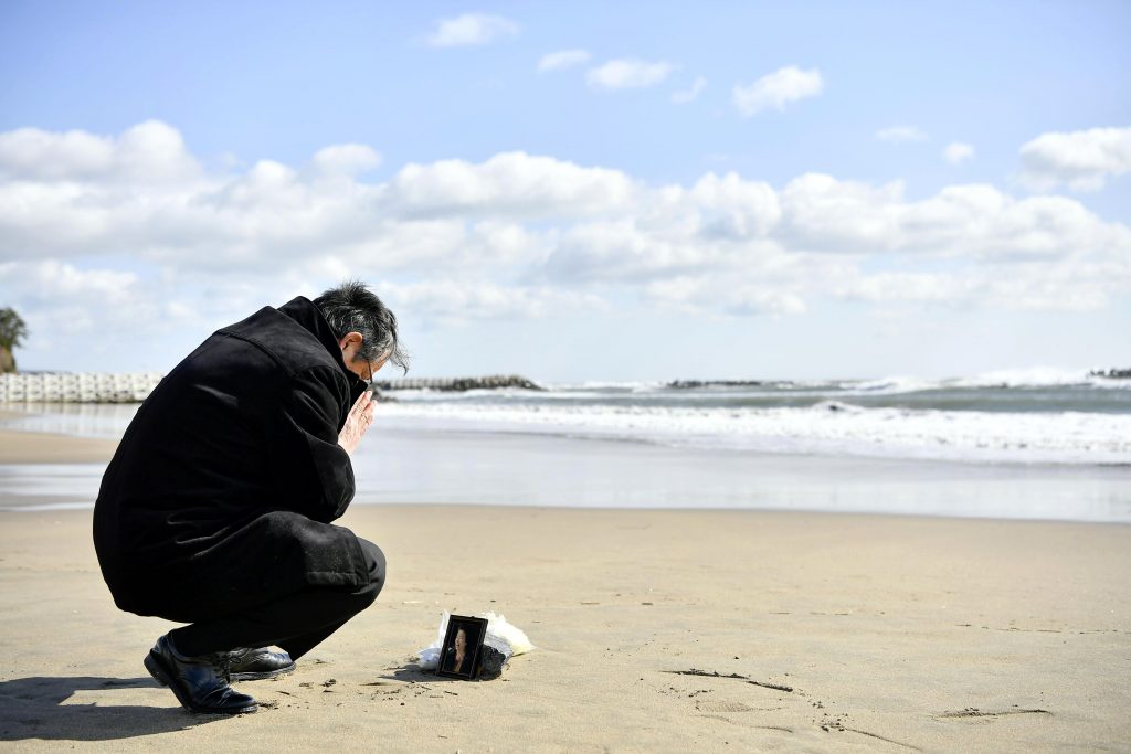 2020年3月11日、日本北部の気仙沼で、2011年の地震と津波の犠牲になった妻の写真の前で祈りを捧げる男性。（資料写真/AP通信）