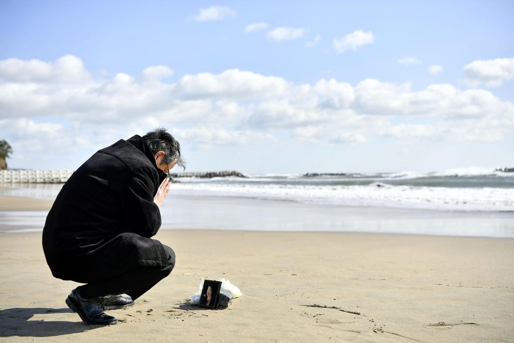2020年3月11日、日本北部の気仙沼で、2011年の地震と津波の犠牲になった妻の写真の前で祈りを捧げる男性。(資料写真/AP通信)