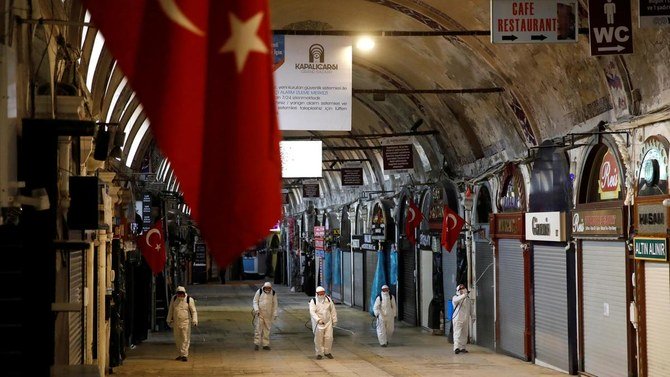 トルコのイスタンブールでコロナウイルスのまん延を防ぐため、「屋根付き市場」としても知られるグランドバザールで消毒剤を噴射する防護服を着た労働者たち。（ロイター）