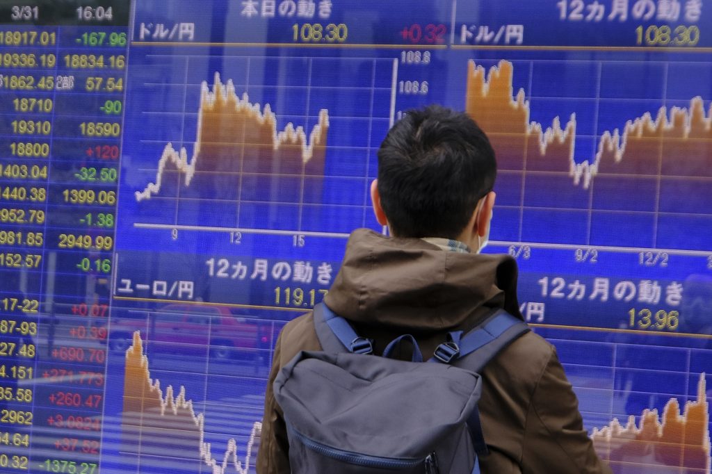 31, 2020年3月31日、東京で米ドル（上）に対する外国為替レートの動きを見つめる男性（AFP通信）