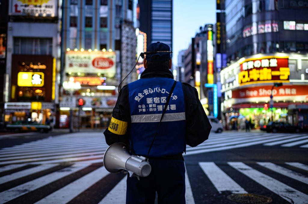 2020年4月18日、東京・新宿の交差点で拡声器を持って立つ警察官（AFP）